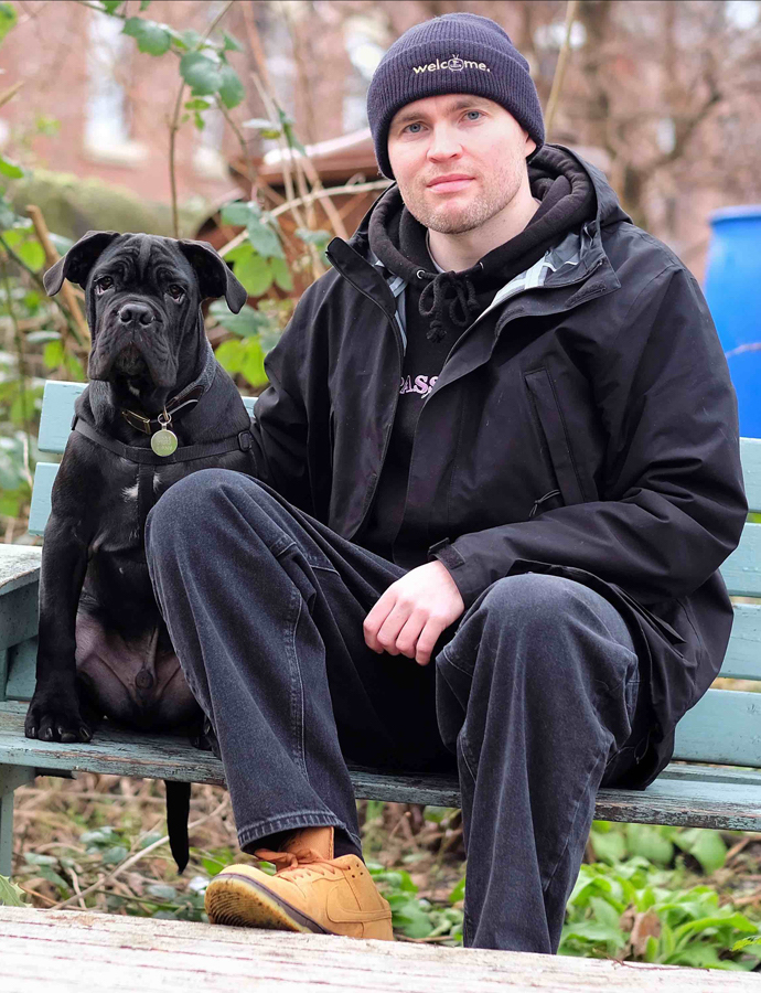 Josh Hallett sat on a park bench with his dog, Dennis.